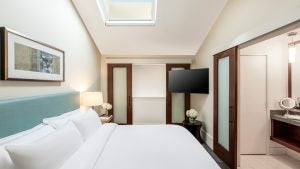 hotel room with bed, tv, bathroom, lamp, skylight